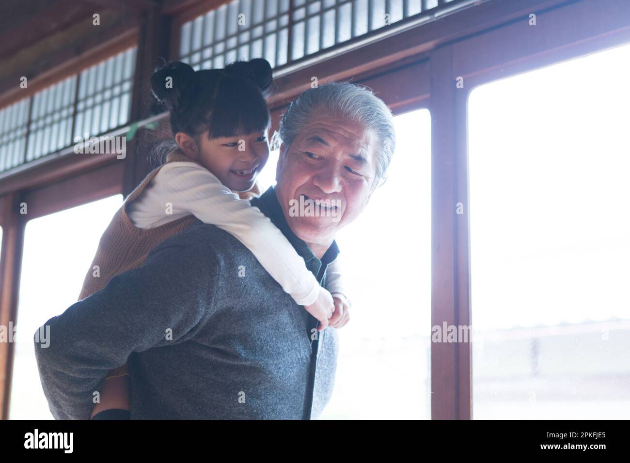 A senior man and his grandson giving a piggyback ride in a country house Stock Photo