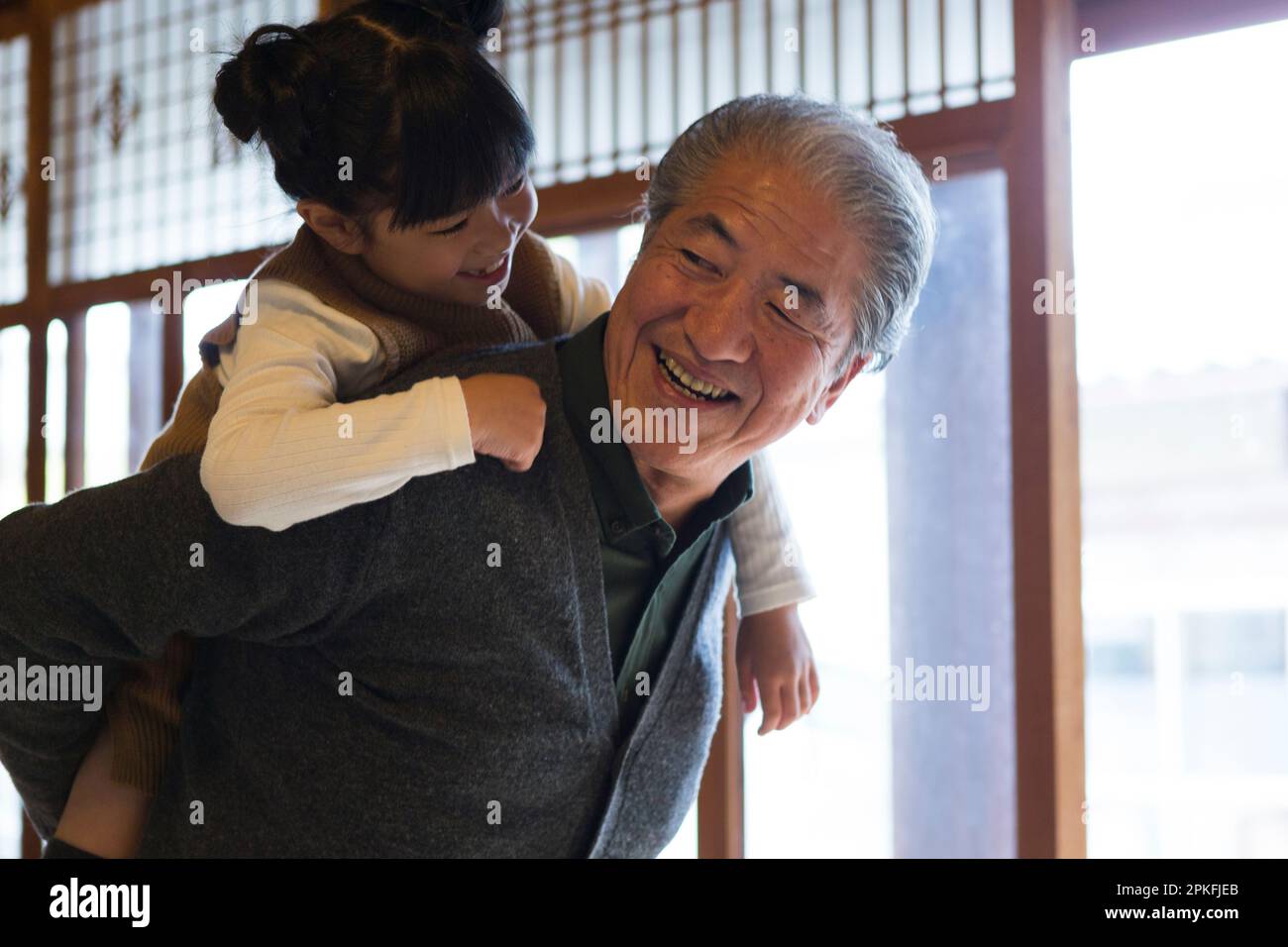 A senior man and his grandson giving a piggyback ride in a country house Stock Photo