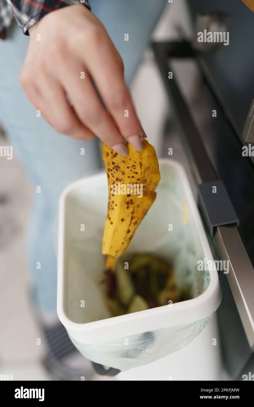 Female hand throwing banana peel in a compost bin. Woman recycling