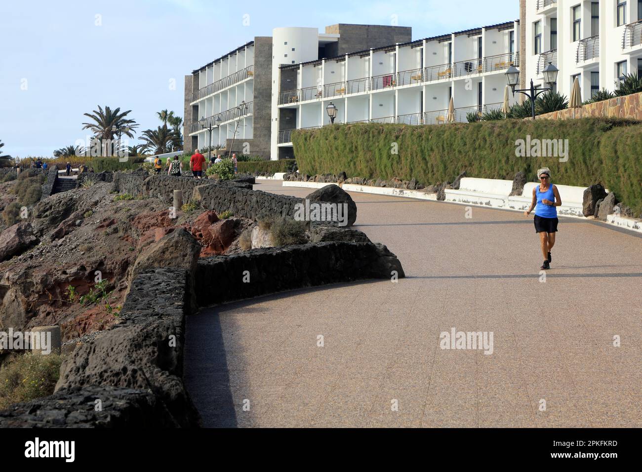 Older lady running on coastal path towards Las Coloradas, Playa Blanca, Lanzarote. Taken February / March 2023. Stock Photo