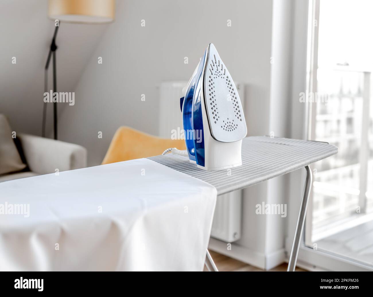 Electrical iron for wrinkled clothes on ironing board indoor. Modern