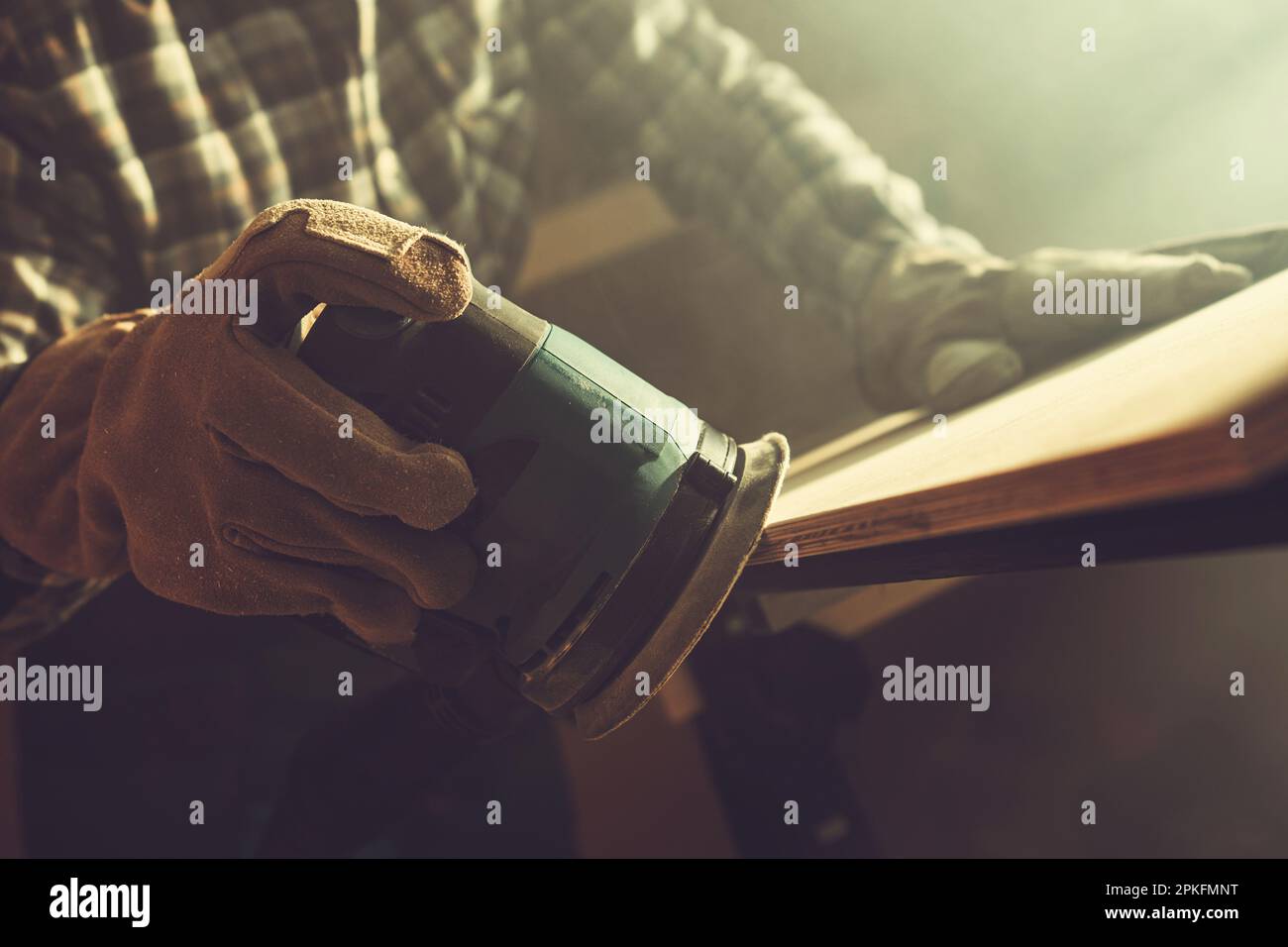 Worker Softening Plank Edges Using Wood Sander Close Up. Construction Theme. Stock Photo