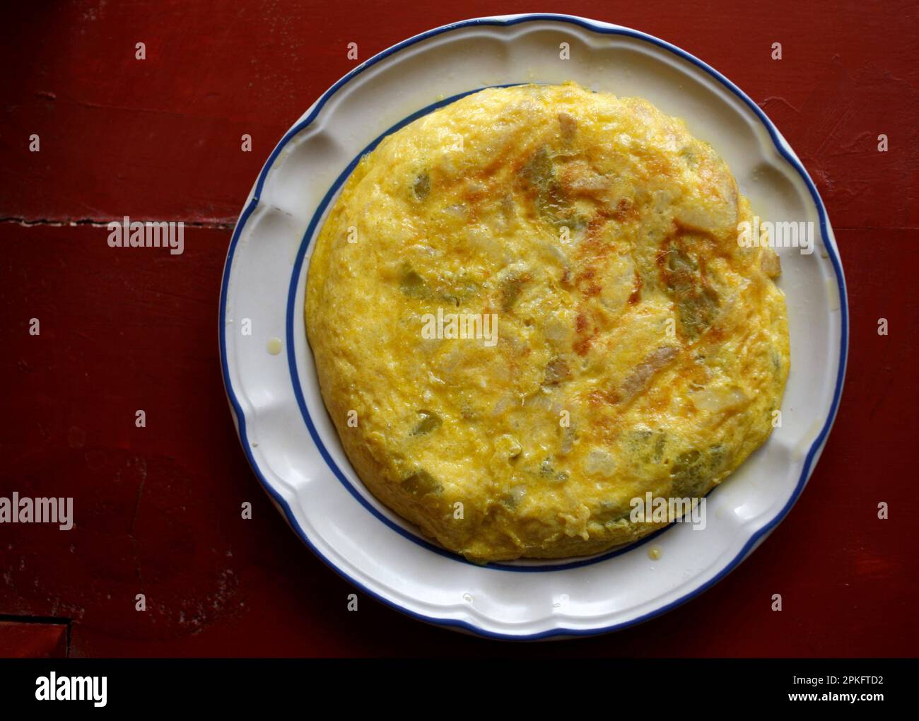 A Spanish Tortilla with eggs, onion and potatoes in a red table in