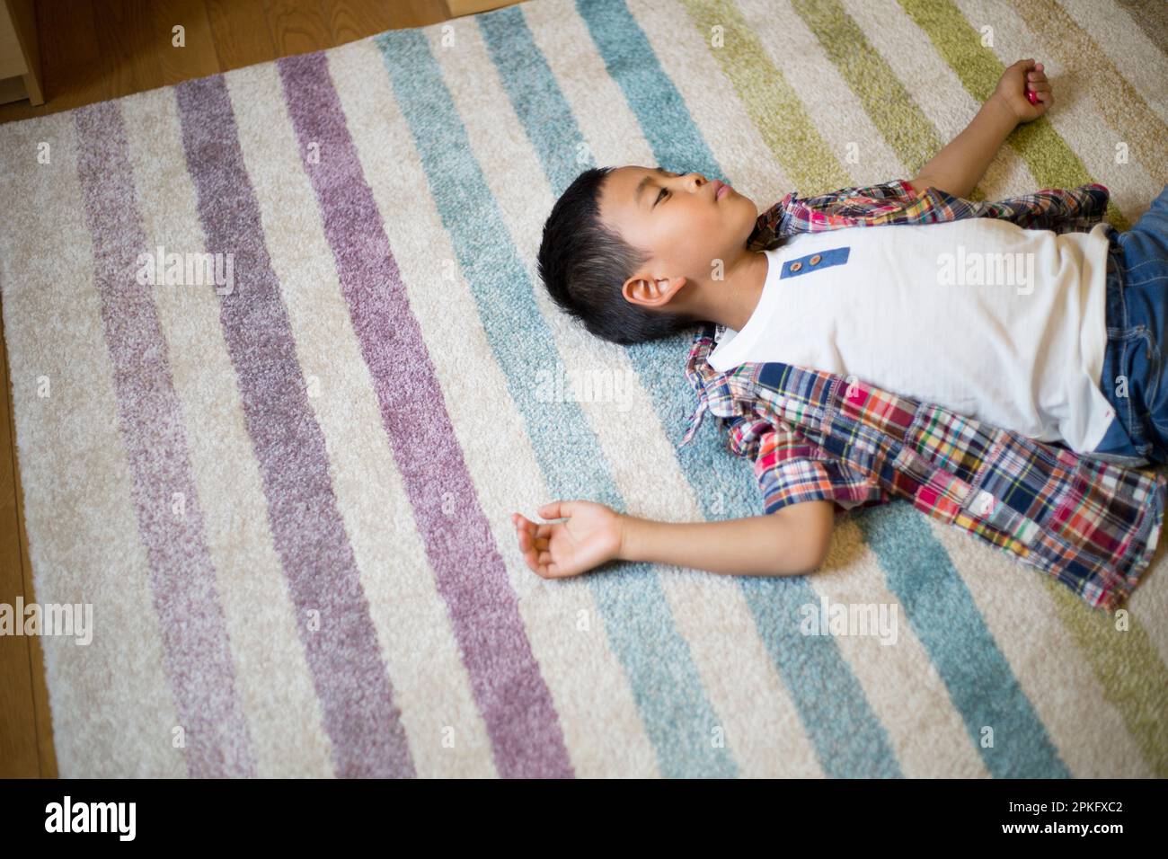 An elementary school boy lying on the carpet in the living room Stock Photo