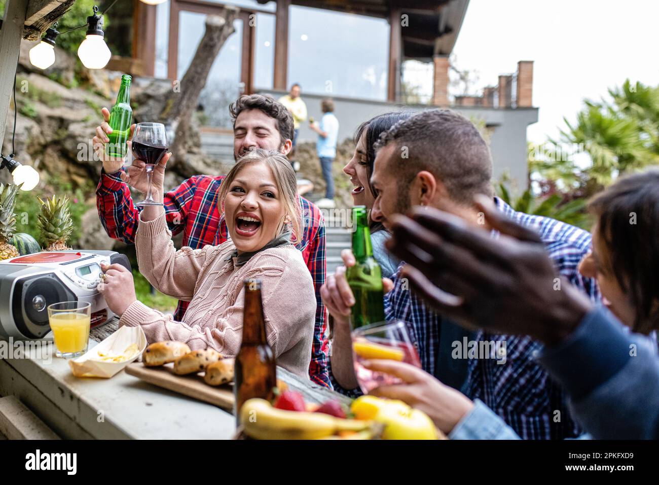 Party in large villa with pool and chiringuito, people who listen to music, dance together and toast with different drinks Stock Photo