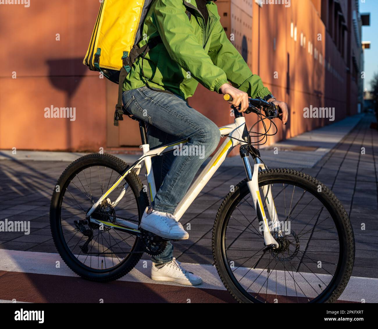 portrait of a unrecognizable fast delivery man on bicycle, food and beverage express delivery service in the city, sustainability way of transportatio Stock Photo