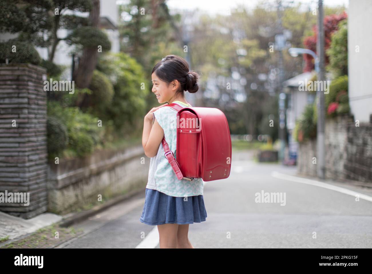 Girl with School Bag Walking in Residential Area Stock Photo