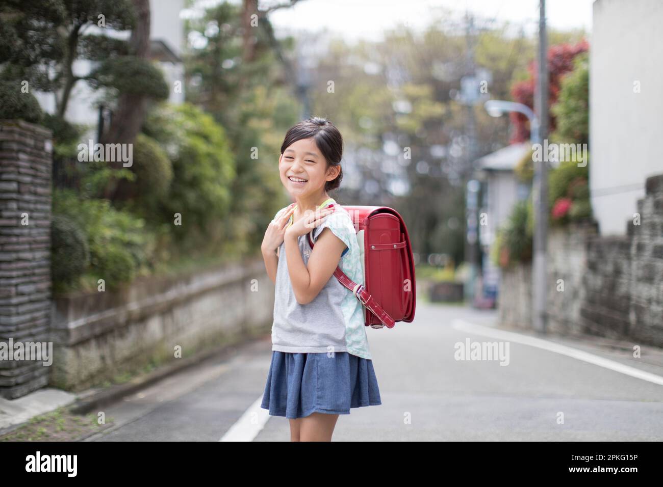 Girl with school bag walking in a residential area Stock Photo