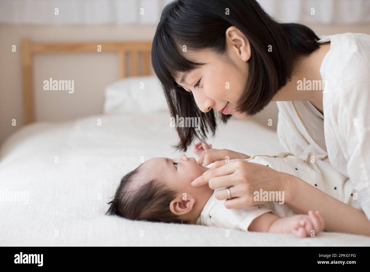 Mother nursing baby lying on her back on the bed Stock Photo