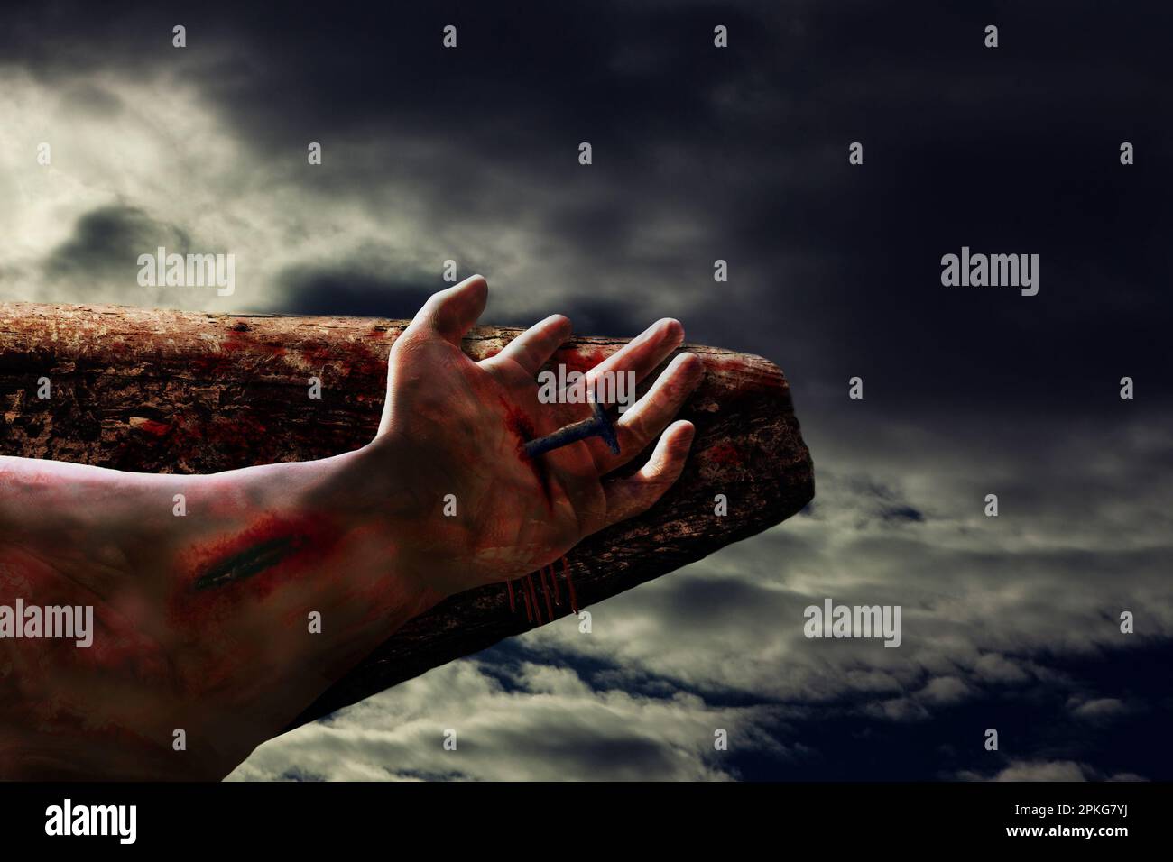 Dramatic scene of Jesus crucifixion showing hand of Christ with blood and bruise nailed to wooden cross symbolic of Christian Easter and Good Friday Stock Photo