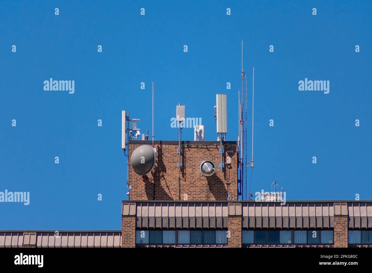 Horizontal shot of the communications equipment on the roof of a tall condo tower under a clear blue sky with copy spoce. Stock Photo