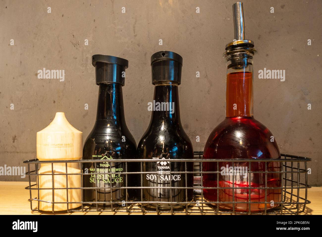 Bottles of soy sauce and chilli oil in a metal mesh basket at a restaurant Stock Photo