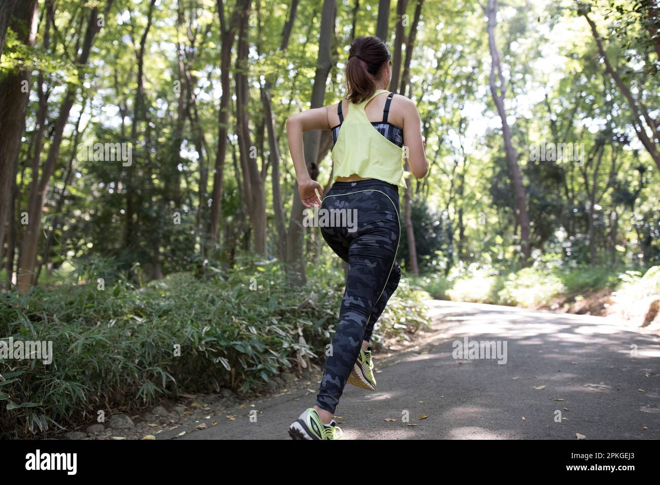 Back view of a woman jogging in a grove of trees Stock Photo