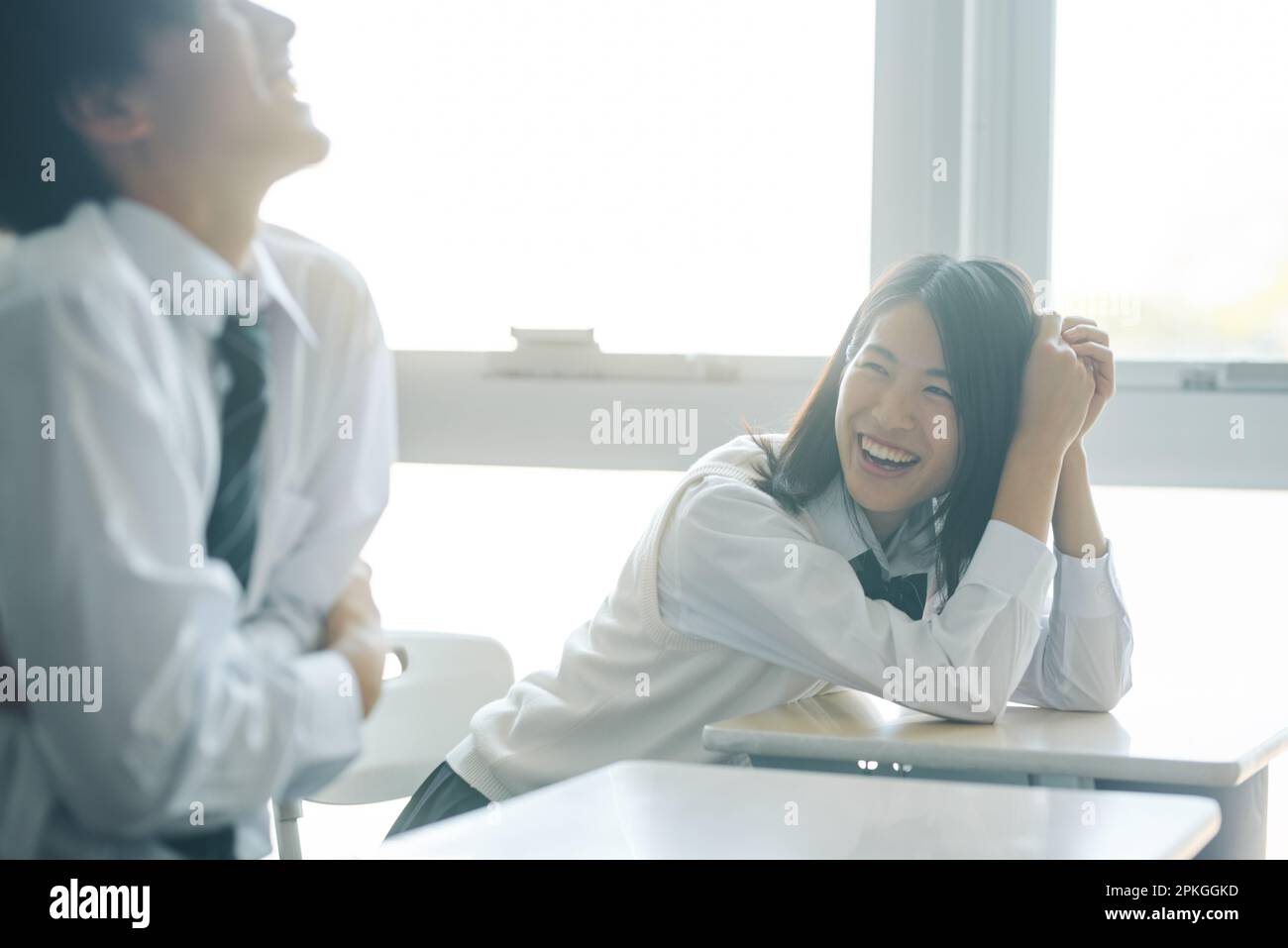 Male and female high school students chatting in a classroom during ...