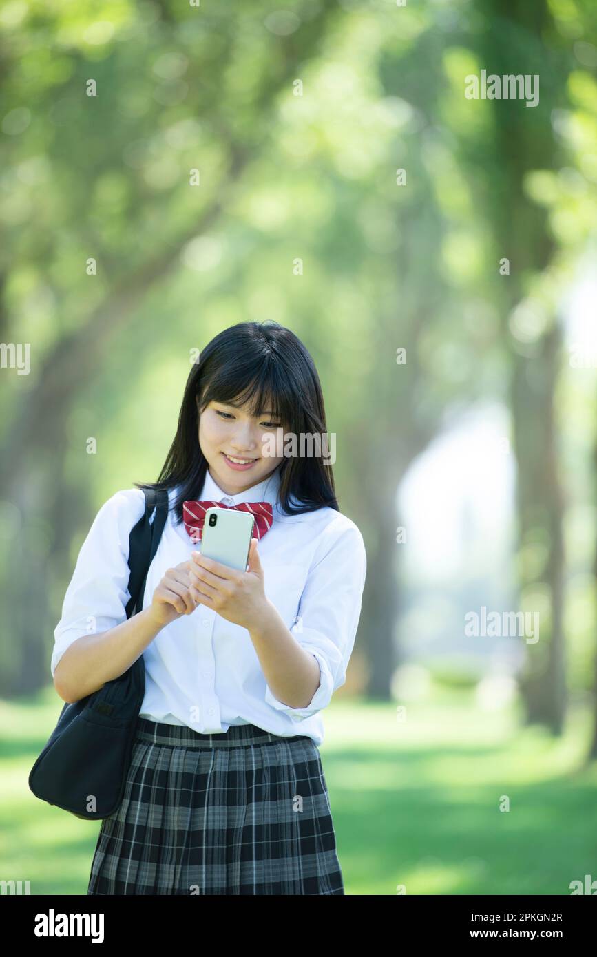 Female student operating a smartphone in a row of poplar trees Stock ...