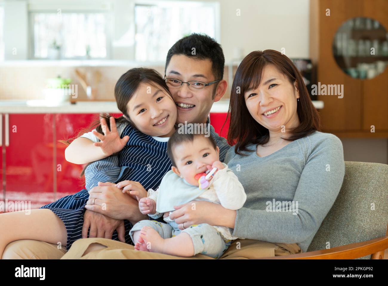 Family sitting on couch and smiling Stock Photo