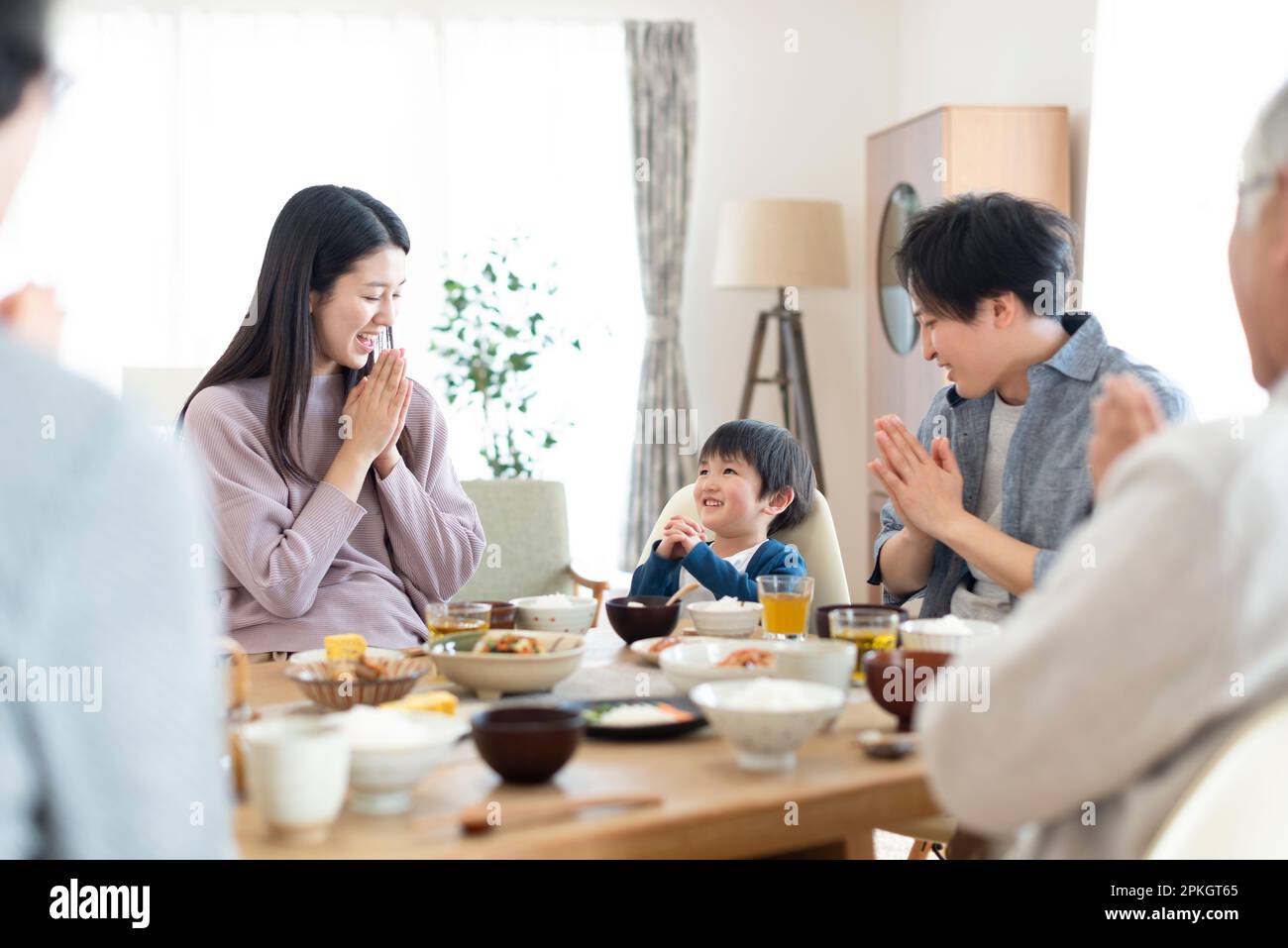 Three-generation family holding hands before eating Stock Photo