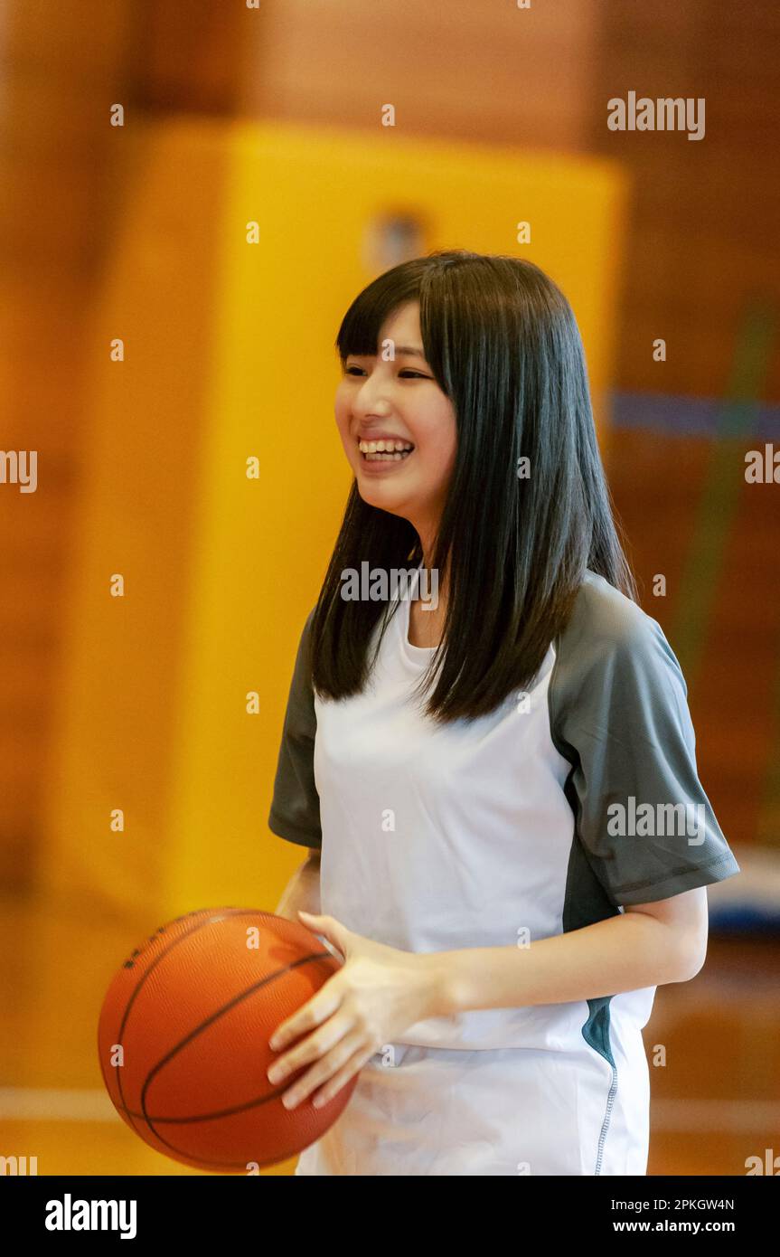 Female student playing basketball in the gym Stock Photo