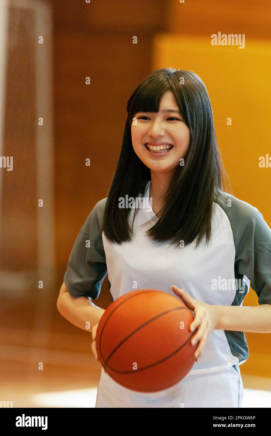Female student playing basketball in gymnasium Stock Photo