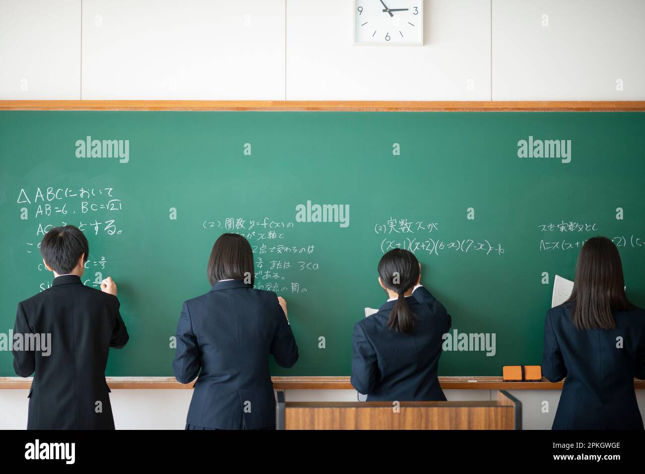 Back view of a student writing answers on the blackboard with chalk ...