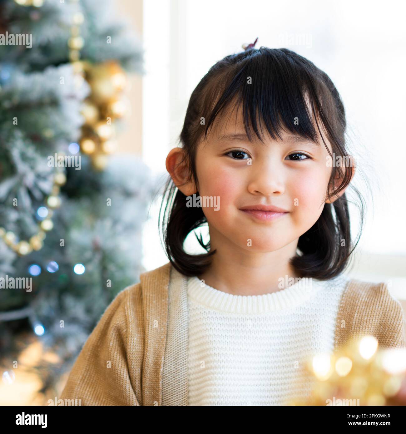 Girl smiling in front of Christmas tree Stock Photo