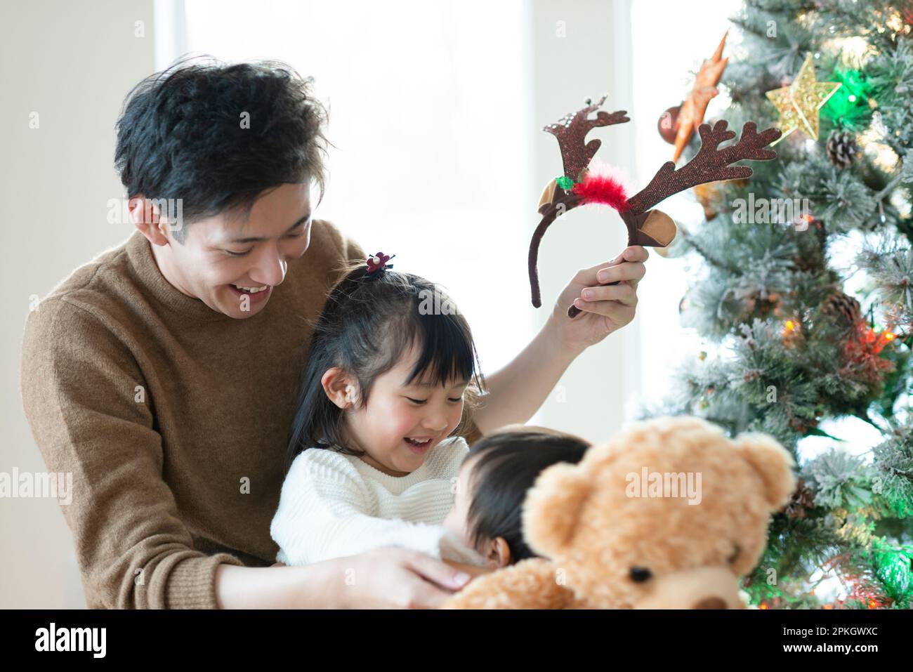 Parent and child smiling in front of Christmas tree Stock Photo