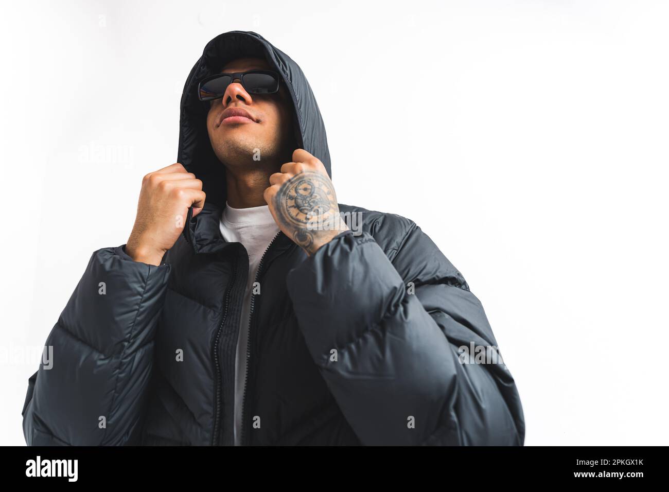 young tattooed man with sunglasses touching his winter jacket, isolated studio shot medium. High quality photo Stock Photo