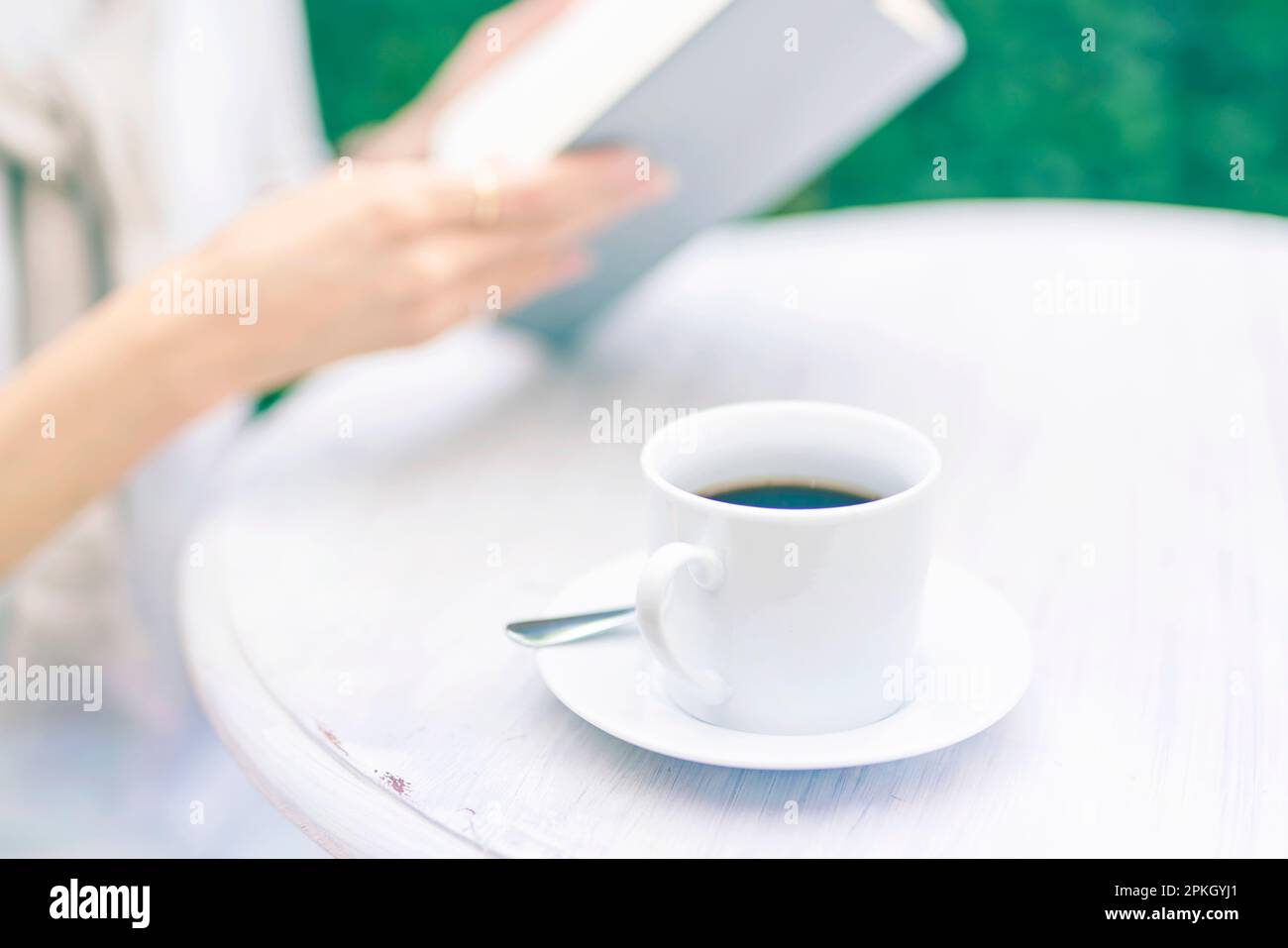 Woman reading on terrace with coffee in hand Stock Photo