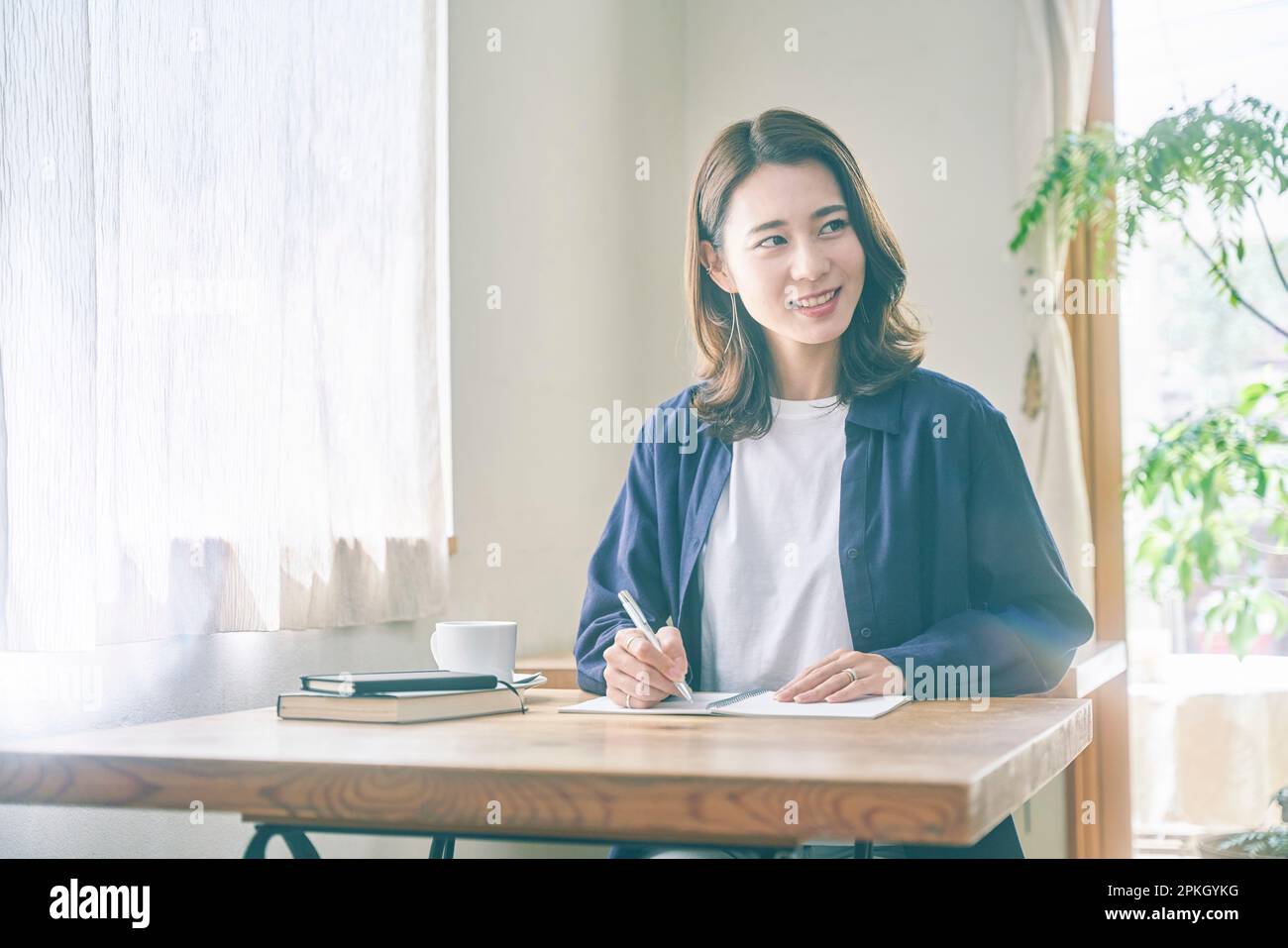 Woman writing and looking back at a notebook in a café Stock Photo