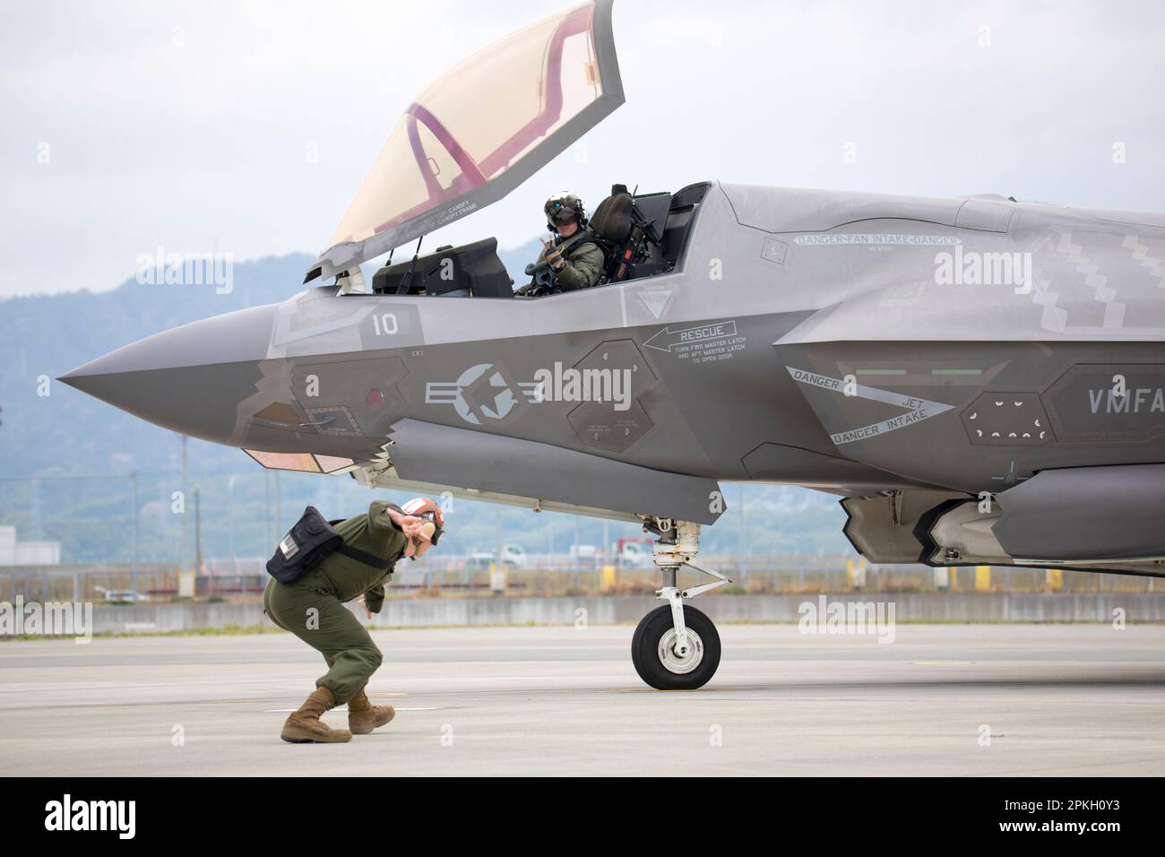 U.S. Marine Corps Lance Cpl. Herbert Tunley III, a fixed wing aircraft mechanic, signals to Maj. Douglas Kansier, F-35B Lightning II aircraft pilot and executive officer of Marine Fighter Attack Squadron (VMFA) 242 at Marine Corps Air Station Iwakuni, Japan, April 5, 2023. Marines with Marine Aircraft Group 12 routinely conduct arming, expeditionary refueling and flight operations to maintain proficiency and readiness in support of a free and open Indo-Pacific. (U.S. Marine Corps photo by Cpl. Tyler Harmon) Stock Photo