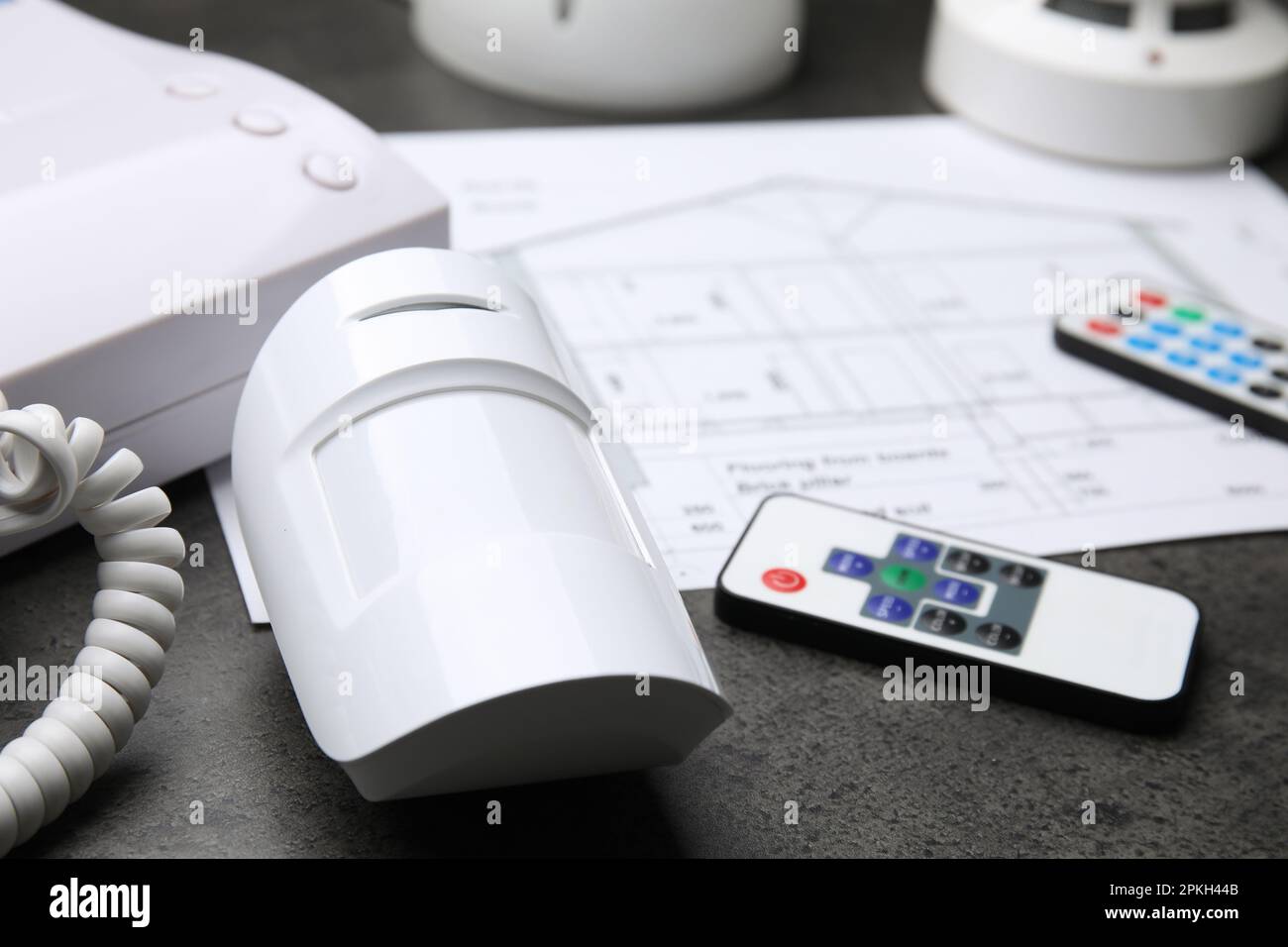 Movement detector, intercom, remote controls and building plan on grey ...