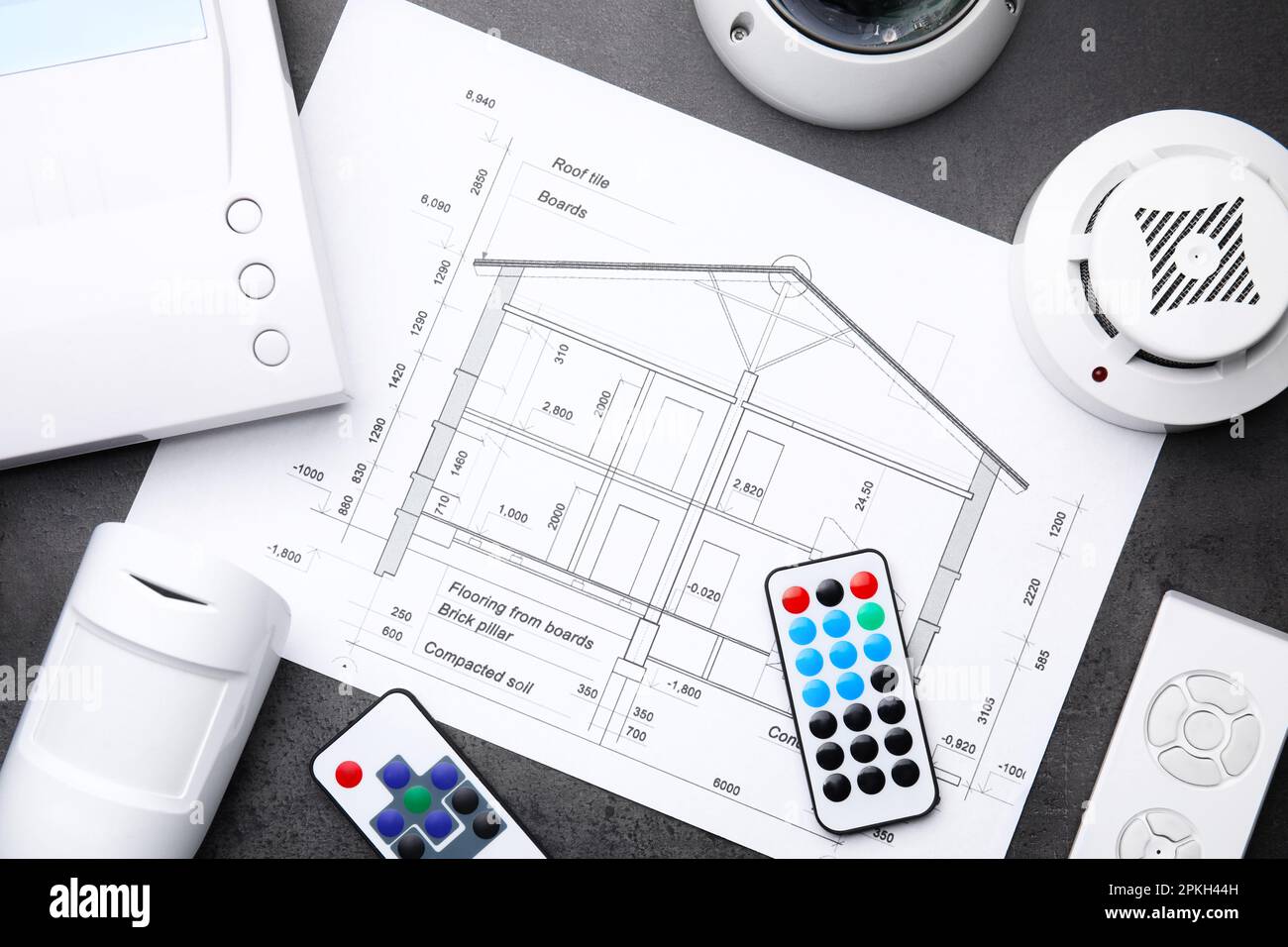 Building plan, remote controls, smoke and movement detectors on grey ...