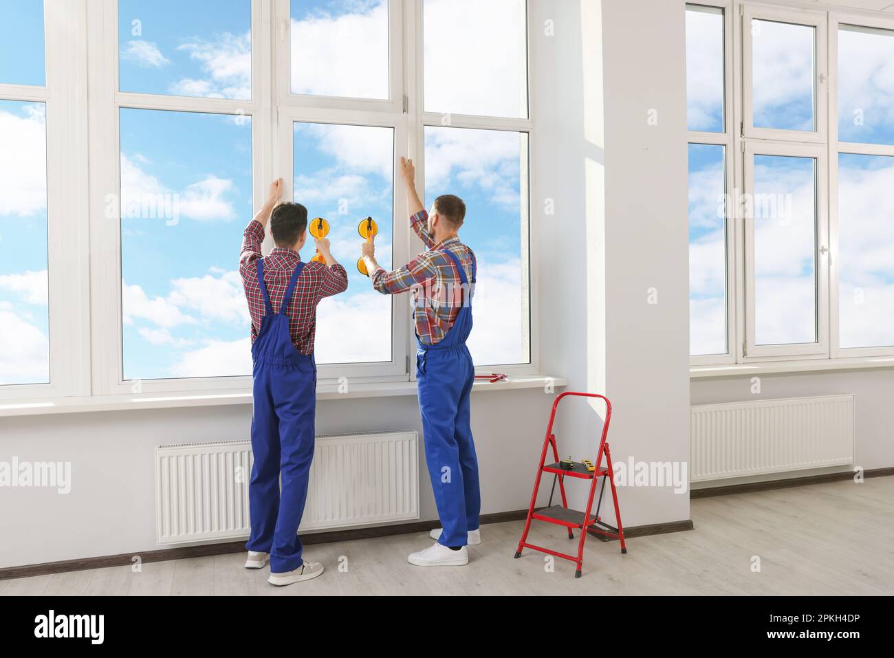 Workers using suction lifters during plastic window installation indoors Stock Photo