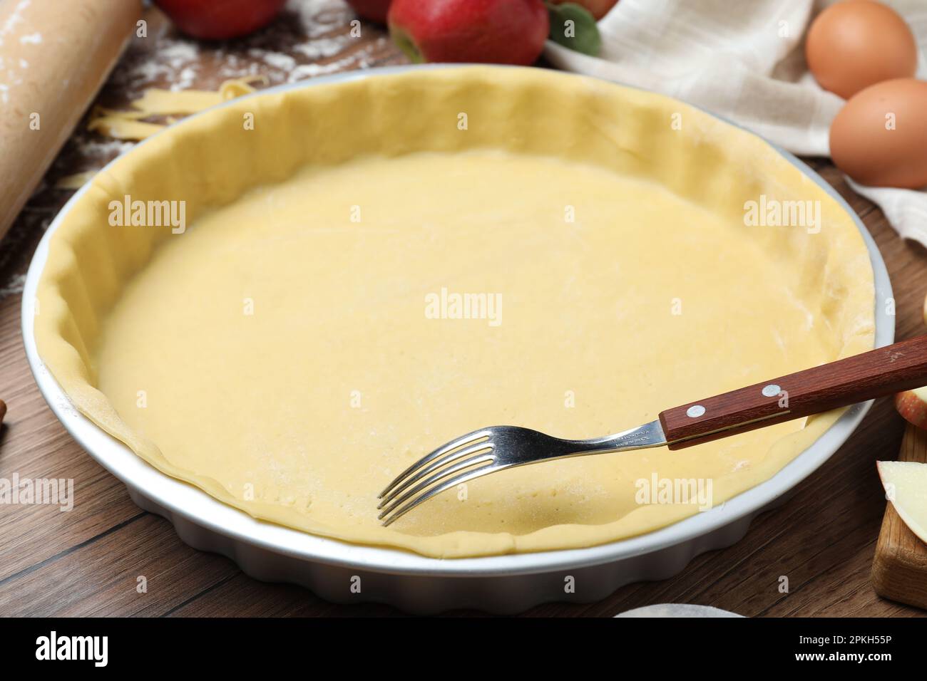 Raw dough with fork and ingredients on wooden table. Baking apple pie Stock Photo