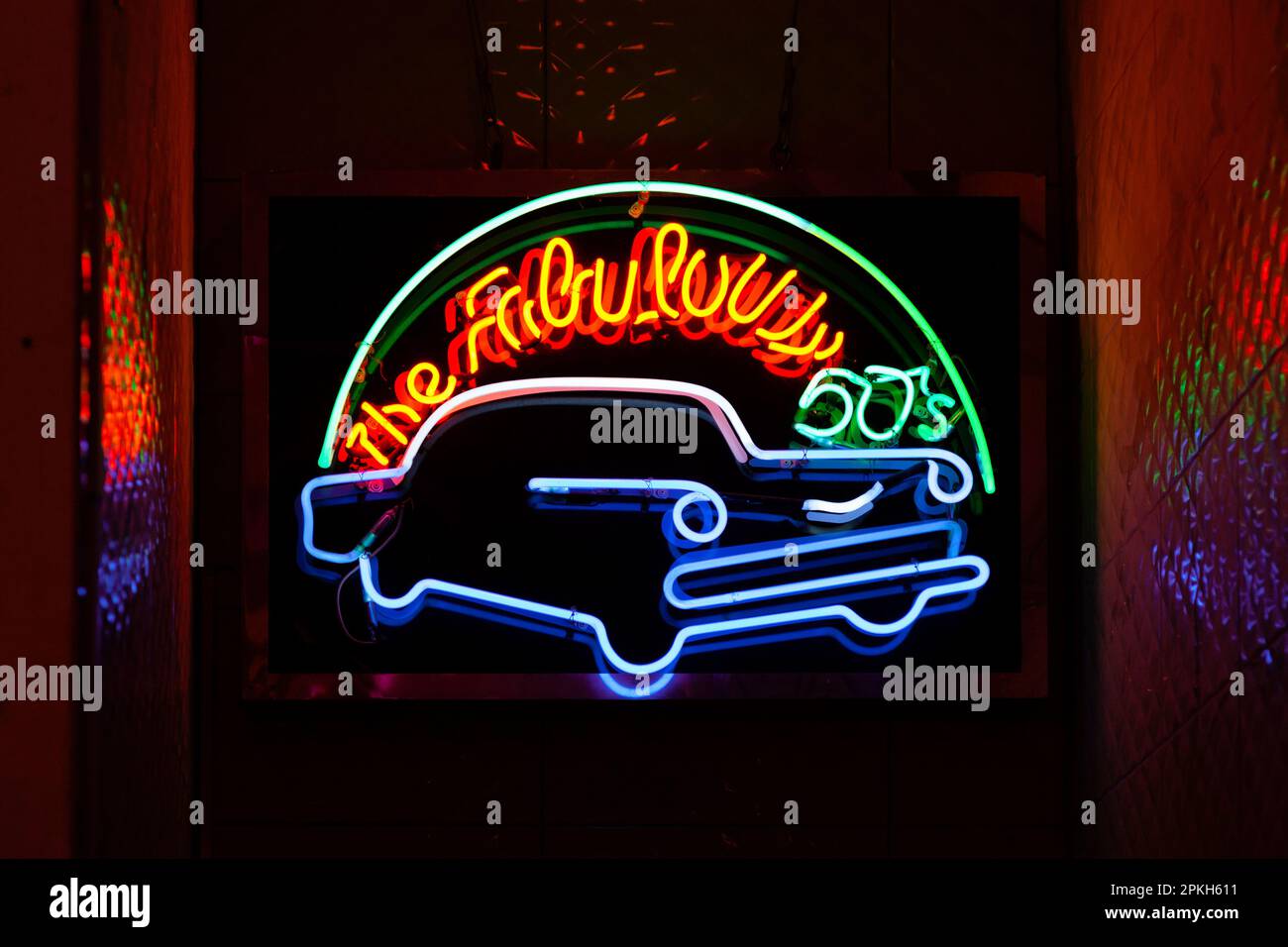 Neon light on a brick wall saying 'The fabulous 50's' above a retro car. Stock Photo