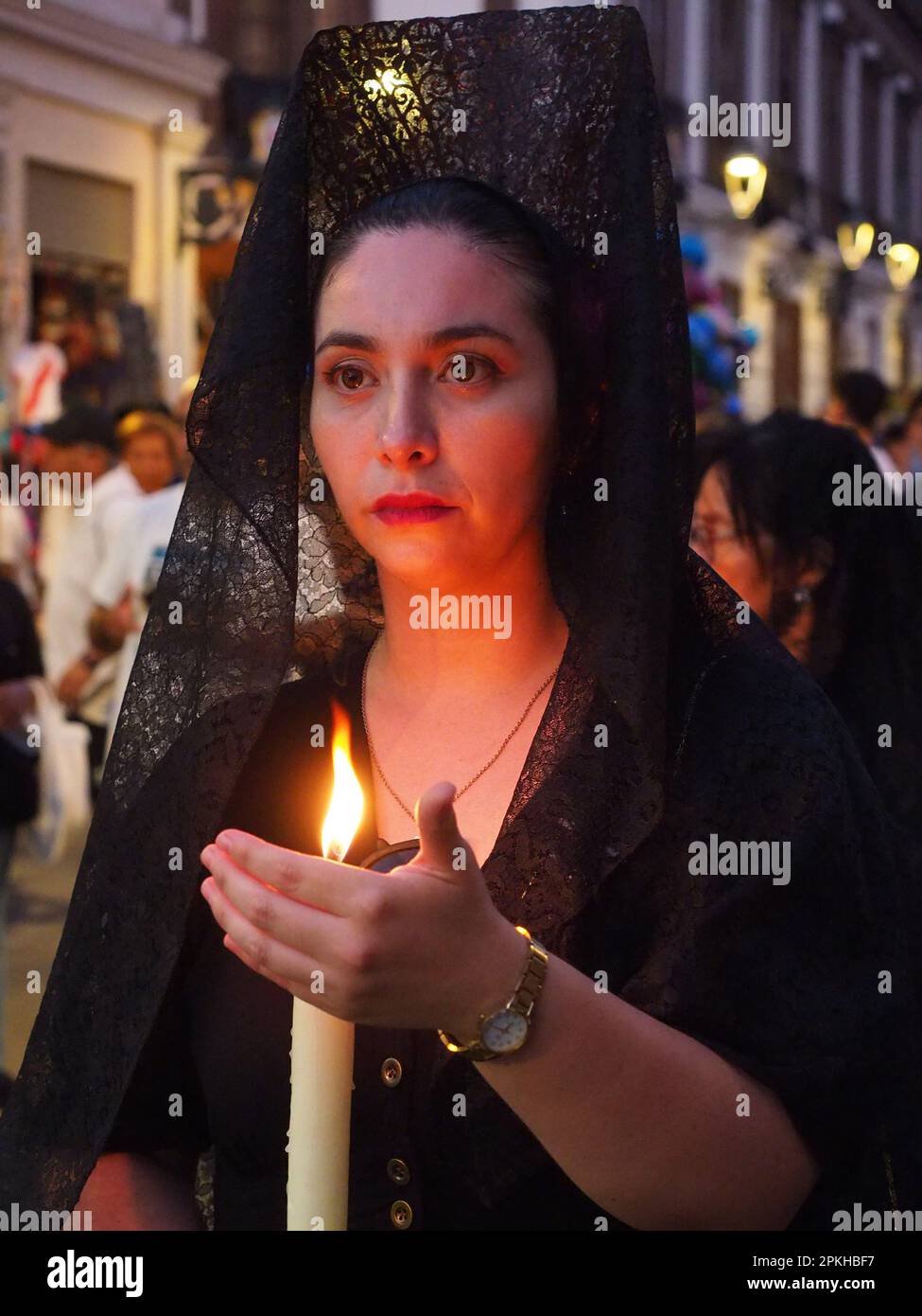 Black dressed female devotees wearing mantilla and comb, carrying