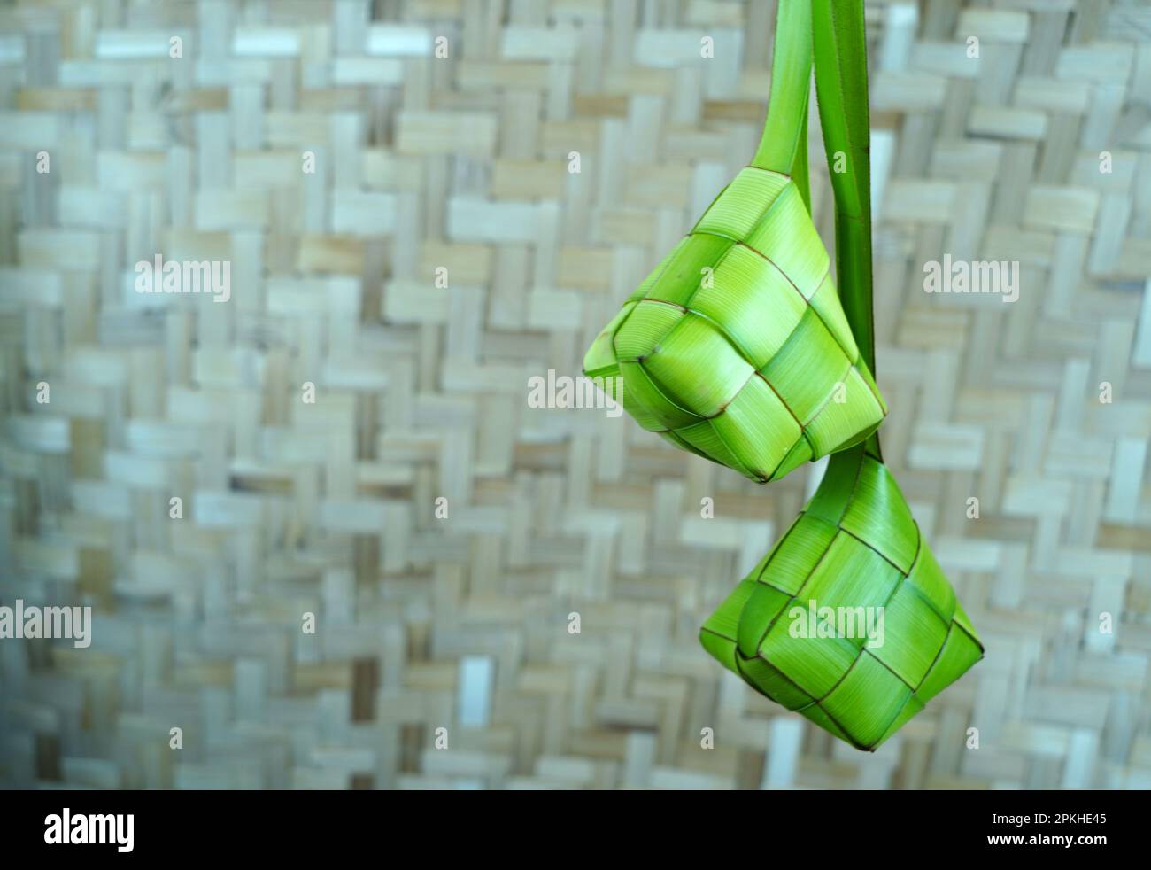 Empty ketupat or empty woven palm leaf hung in a room with woven bamboo wall background. Preparation for Idul Fitri or Eid Mubarak in Indonesia. Copy Stock Photo