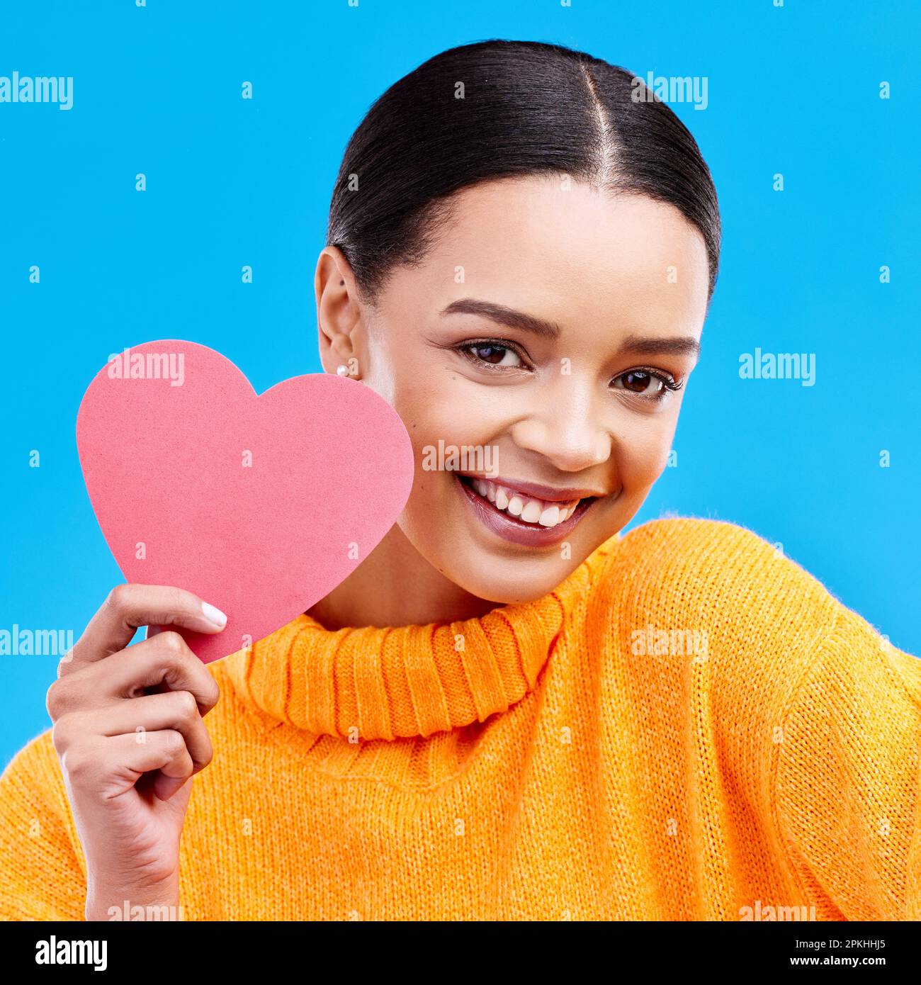 Paper heart, smile and portrait of woman in studio, blue background and