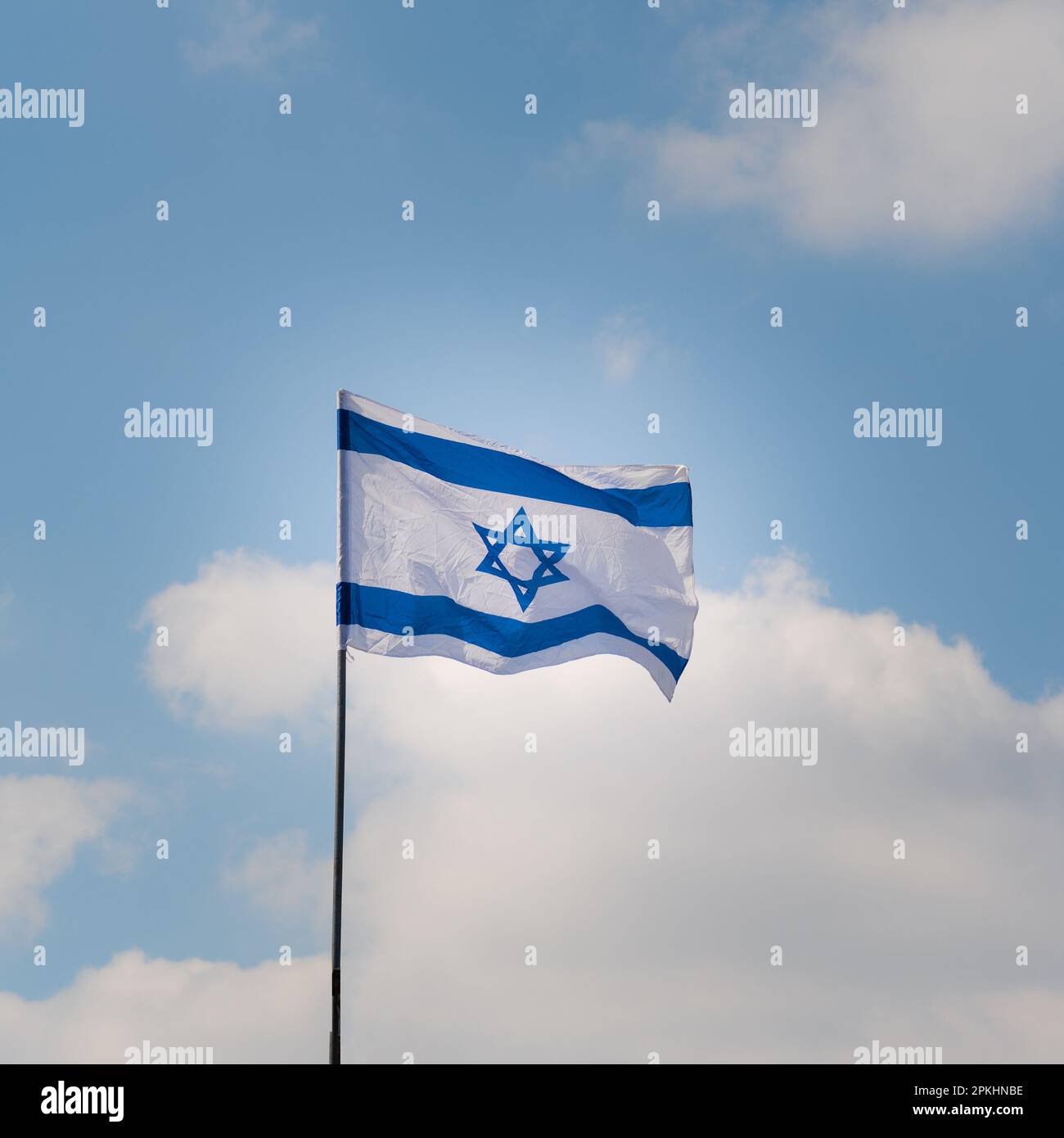 Israeli flag waving in the wind against the blue sky and white clouds ...