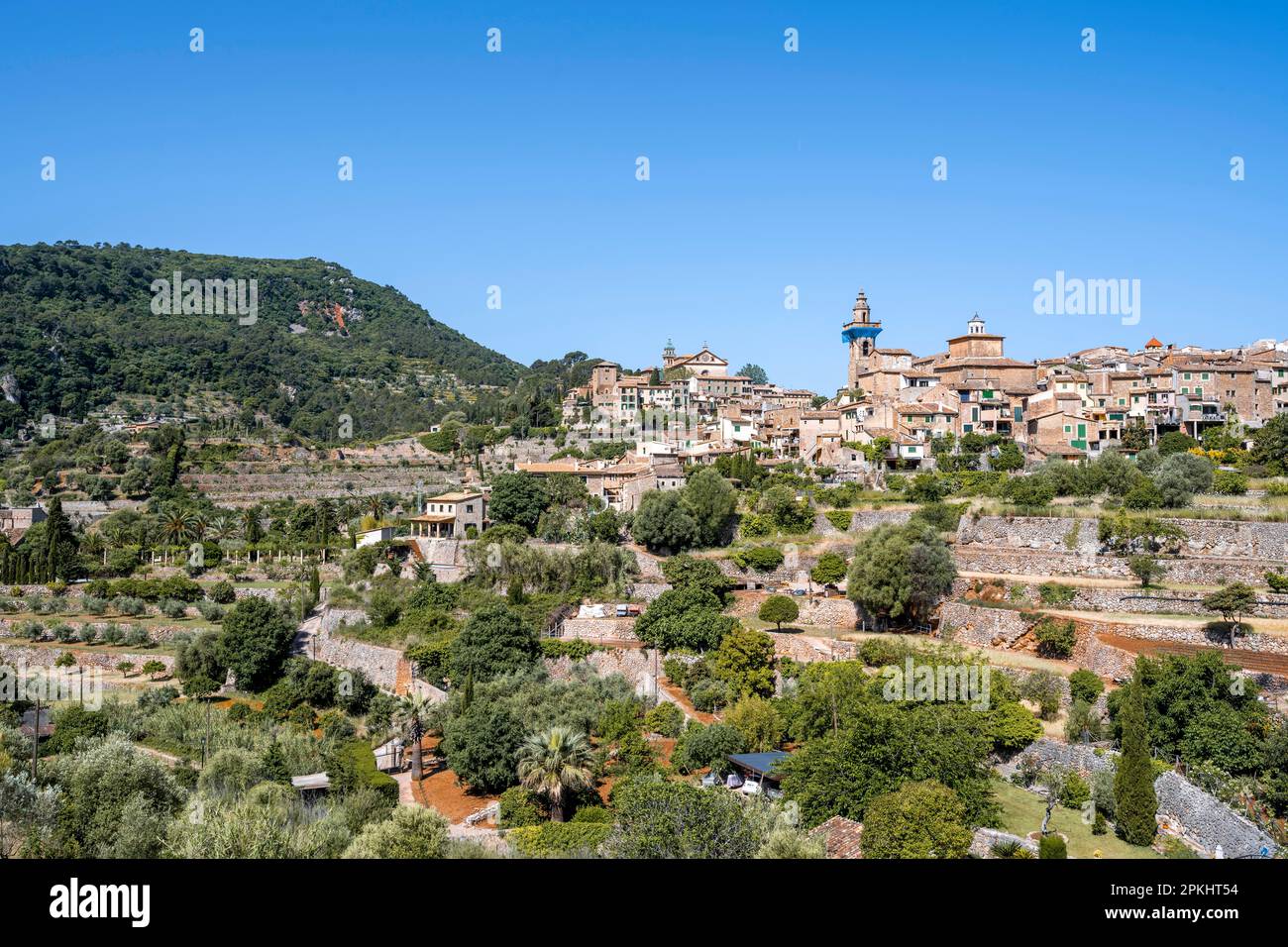 View of Valldemossa mountain village with typical stone houses, with Valldemossa Charterhouse and Esglesia de Sant Bartomeu church, Serra de Stock Photo