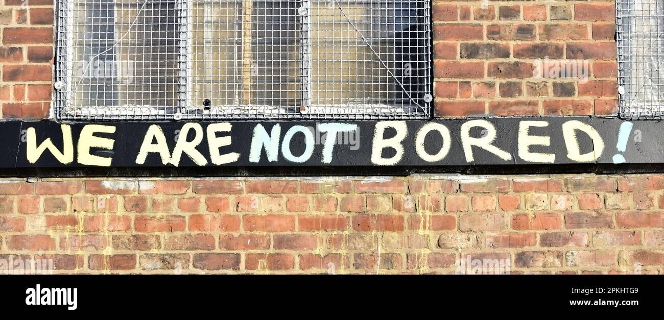 Graffiti on the brick wall of a building in Manchester, UK, says: 'We Are Not Bored!'. Stock Photo