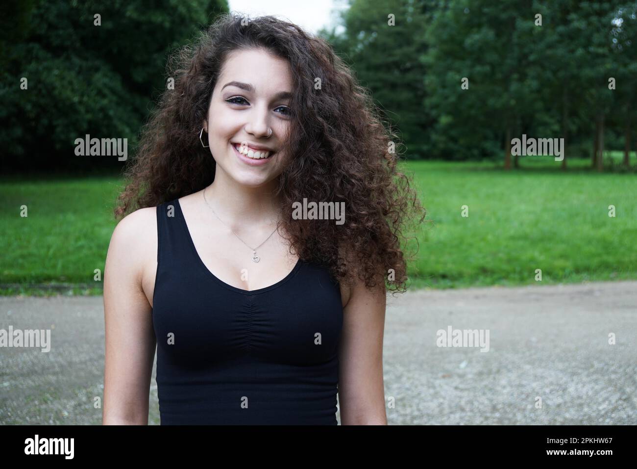 Portrait of a beautiful young woman with brunette long curly hair in ...