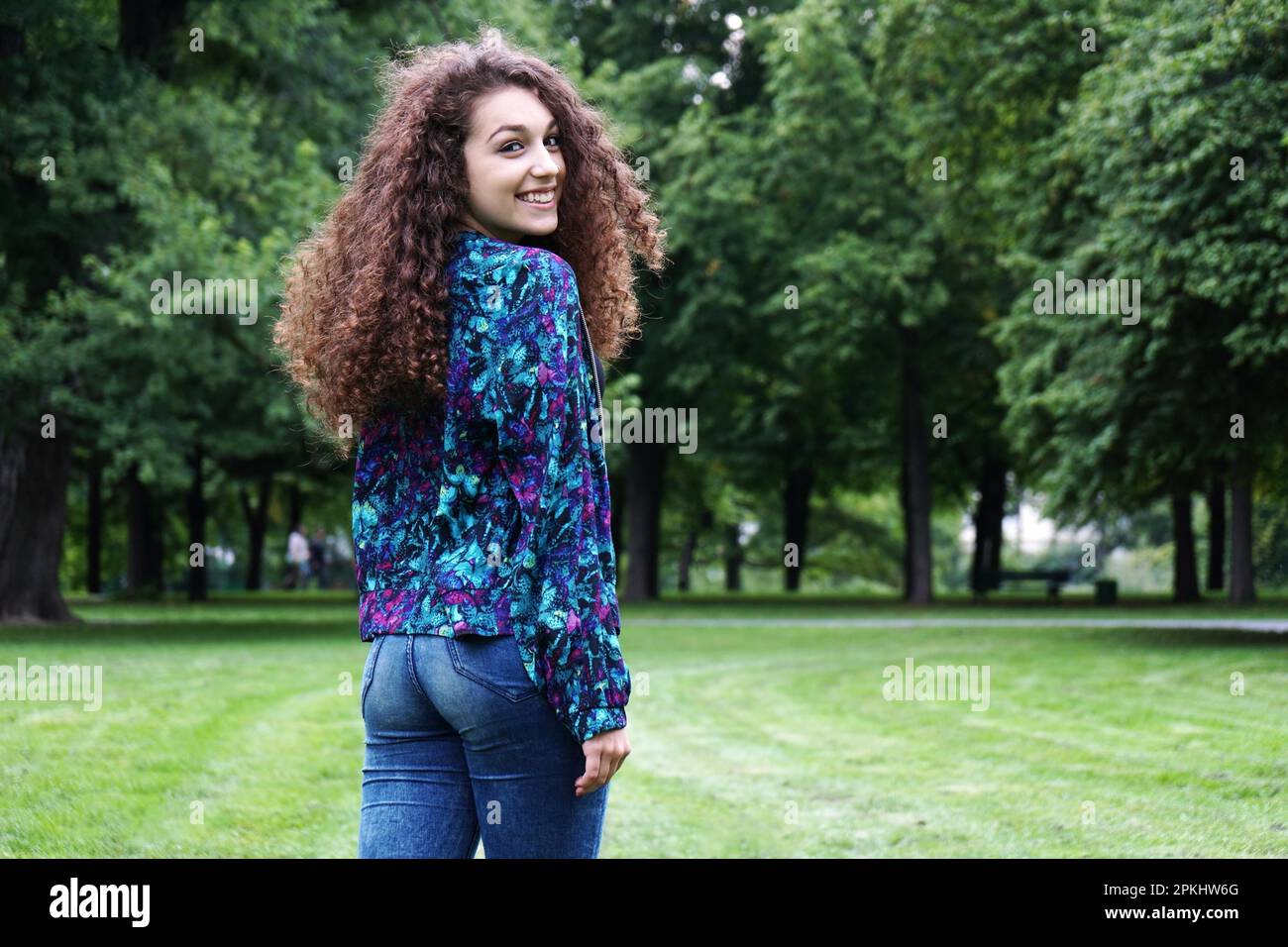 rear view of a young woman in a park looking back over her shoulder Stock Photo