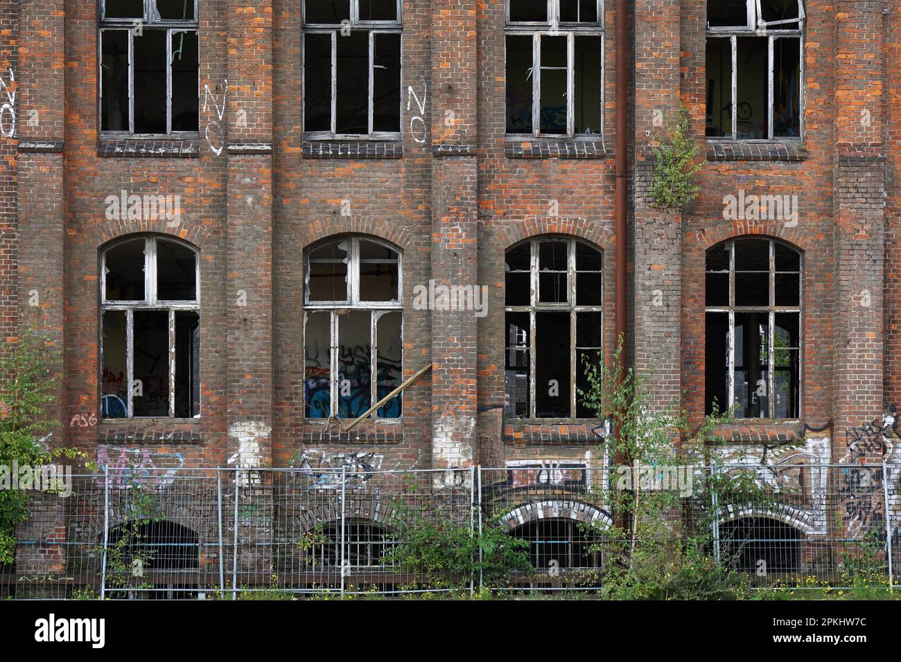 dilapidated red brick facade with graffiti and smashed windows Stock Photo