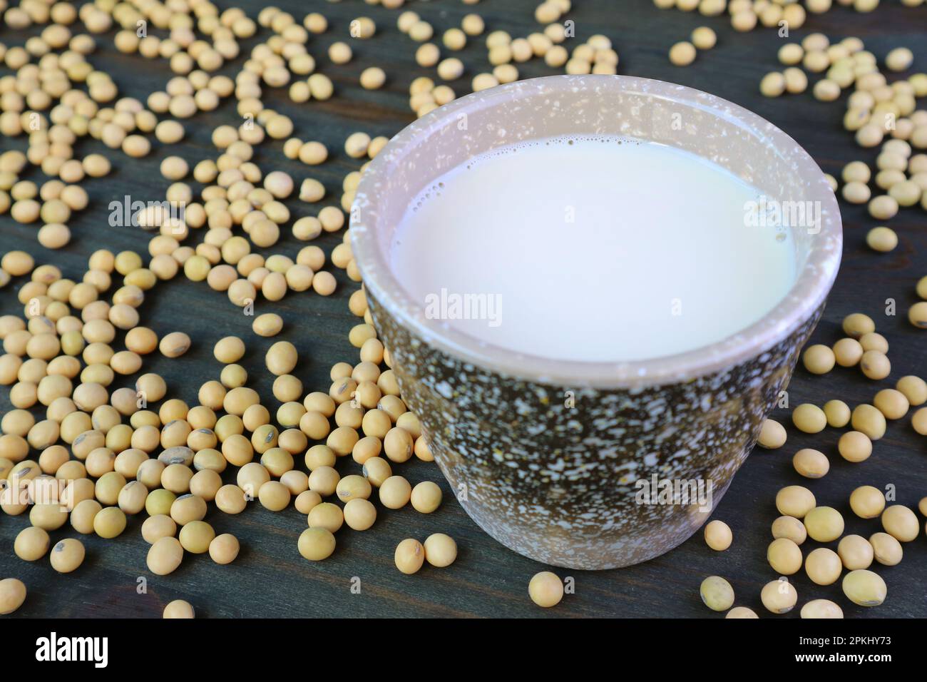 Closeup of a Cup of Soy Milk with Heap of Raw Soybeans Scattered Around Stock Photo