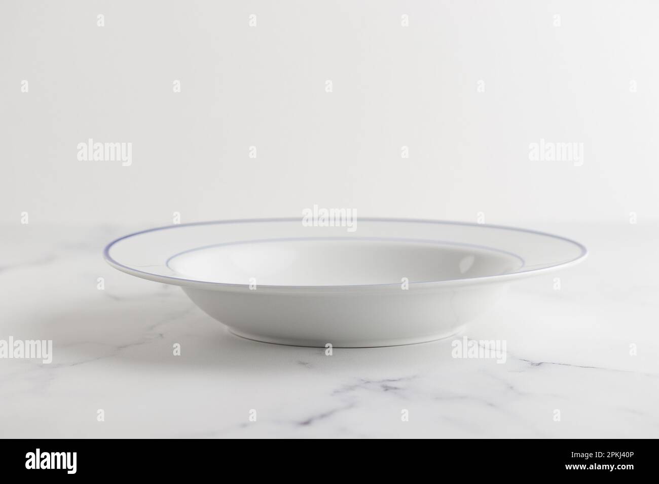 Empty white soup plate with blue stripe on a white background Stock Photo