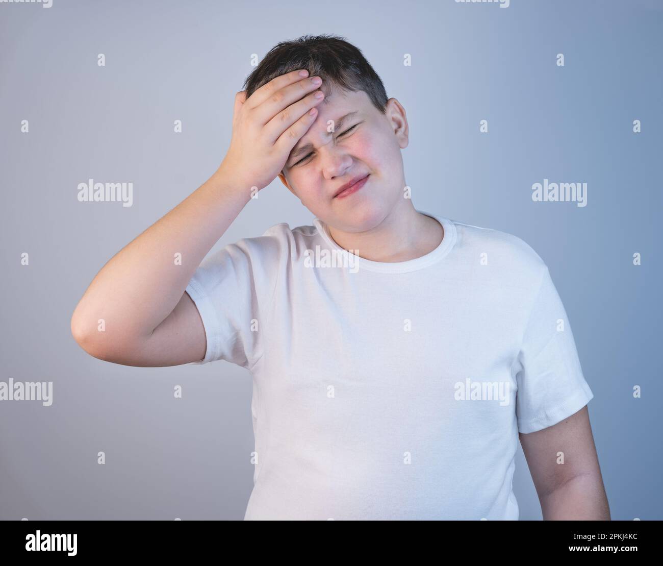 A young man is holding his head in pain. A teenager in a white Tshirt
