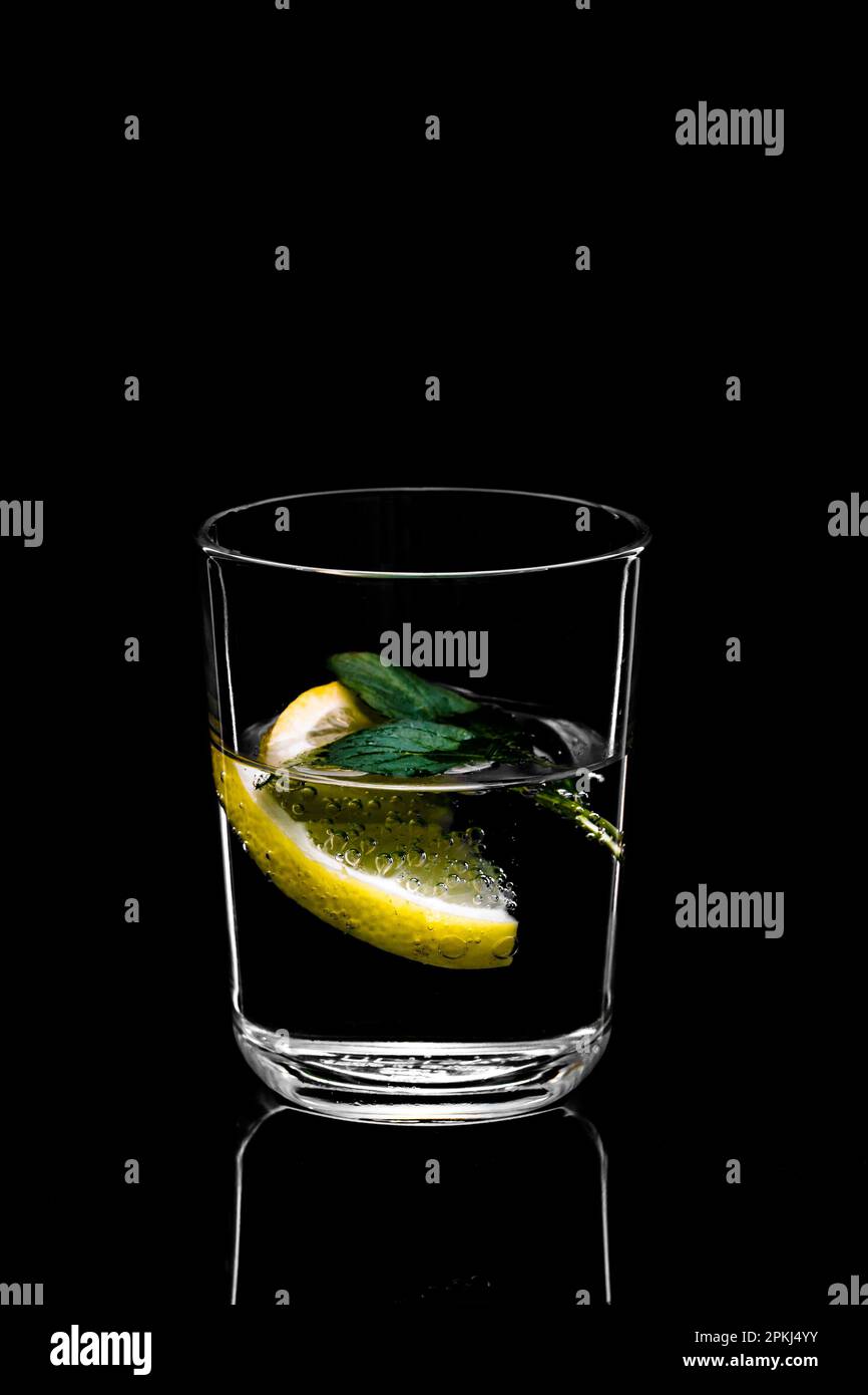 essenundtrinken-frisches klares wasser im glas mit einem spritzer zitrone  minze als sommerliche erfrischung zm trinken und geniessen Stock Photo