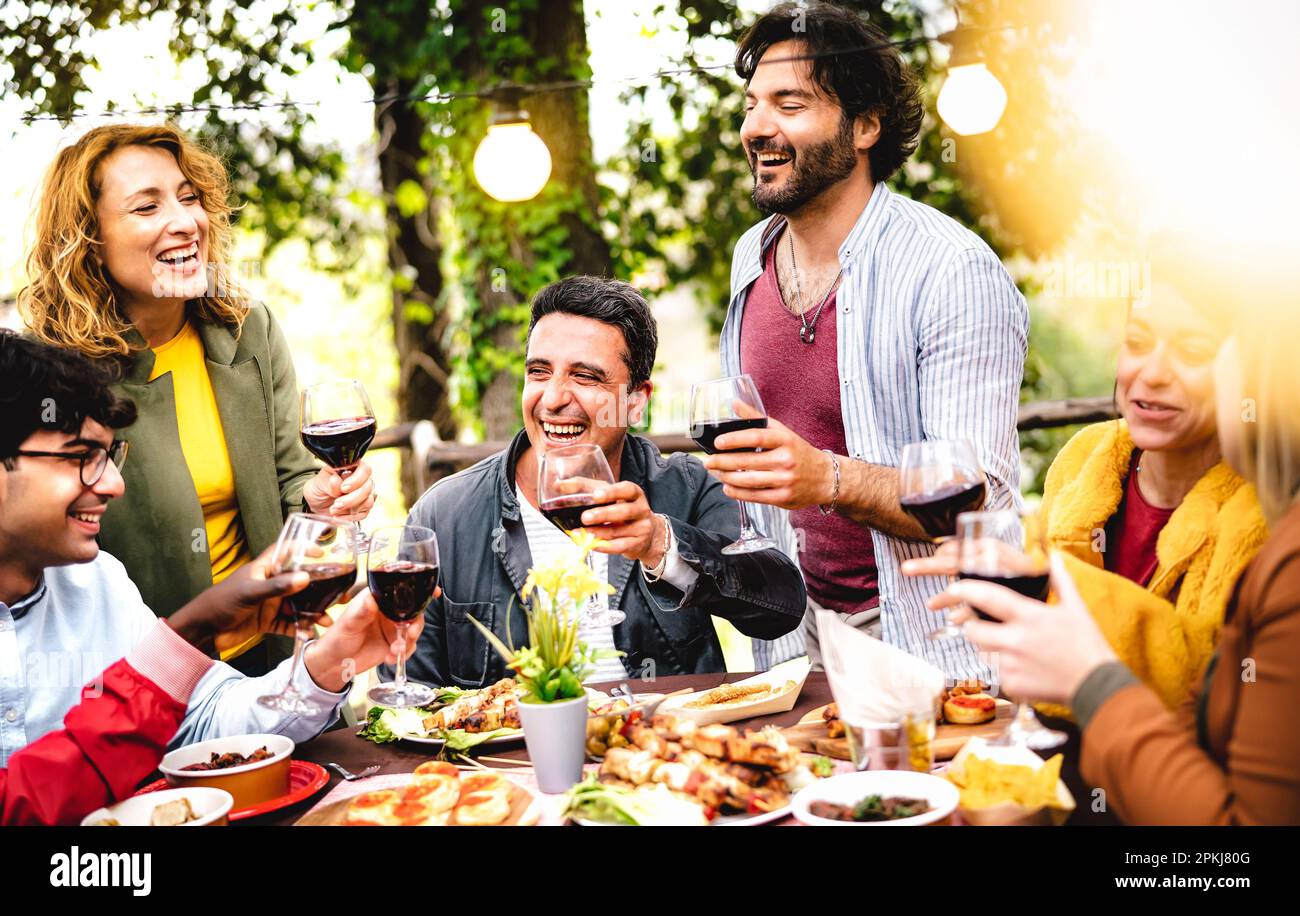 Happy men and women having fun drinking out at wine farm garden - Food and beverage life style concept on mixed age friends enjoying time together Stock Photo