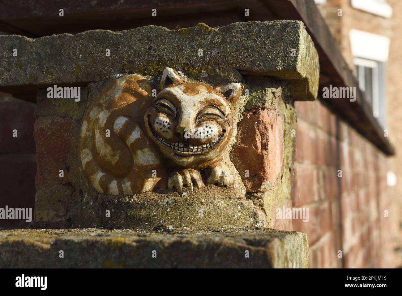 Grinning Cheshire cat sculpture set in the city walls overlooking the River Dee in Chester UK Stock Photo